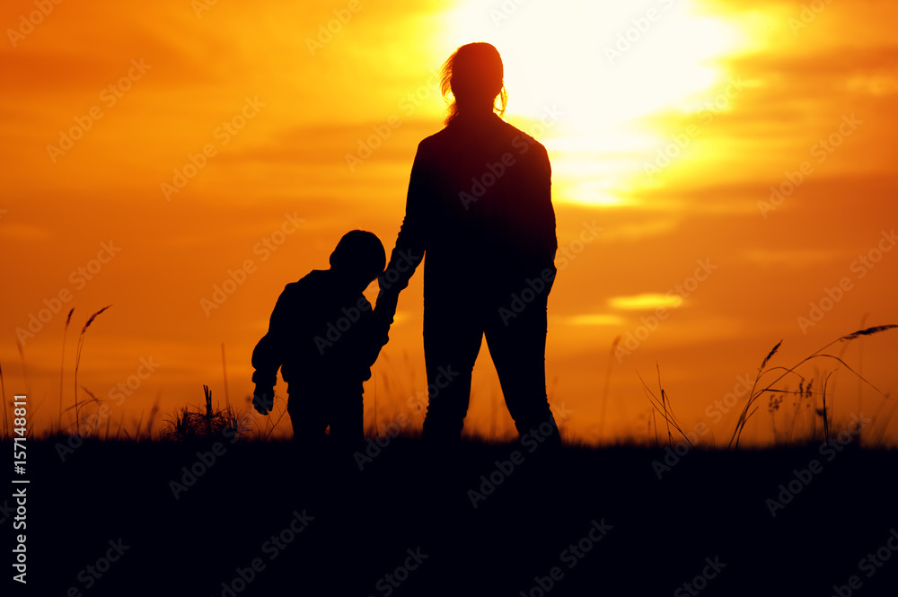 Silhouettes of mother and son at setting sun