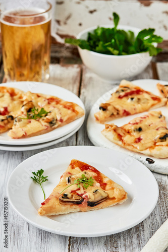 Italian Seafood pizza slice with mussels,tomatoes on a white plate. vertical