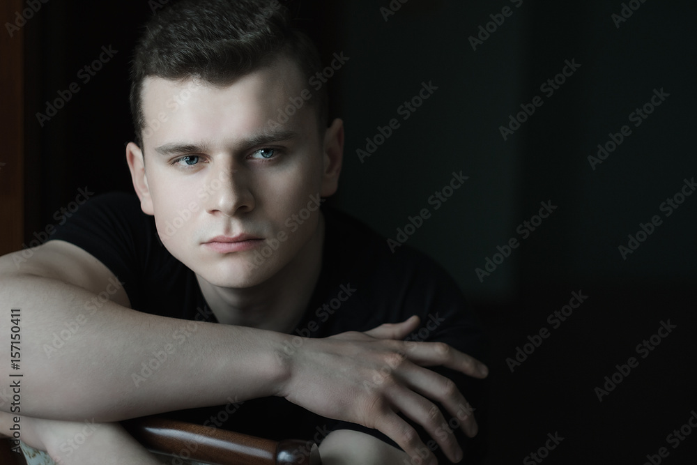 Headshot of man with crossed arms on chair back in low-key lighting Headshot of man with crossed arms on chair back in low-key lighting