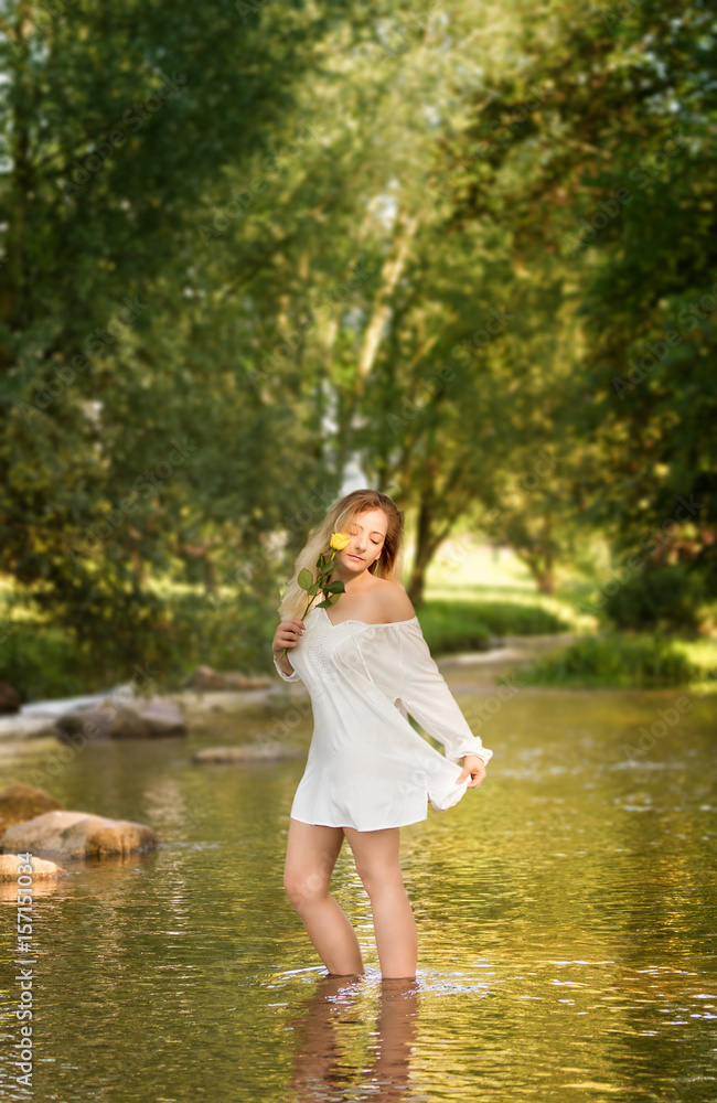 Young woman in the white dress in the middle of a creek.. Young woman in the white dress in the middle of a creek..