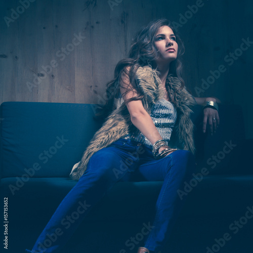 Portrait of elegant woman sitting on black sofa wearing a blue 