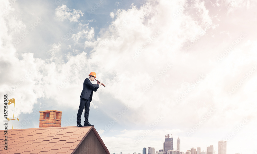 Engineer man standing on roof and looking in spyglass. Mixed med Engineer man standing on roof and looking in spyglass. Mixed med