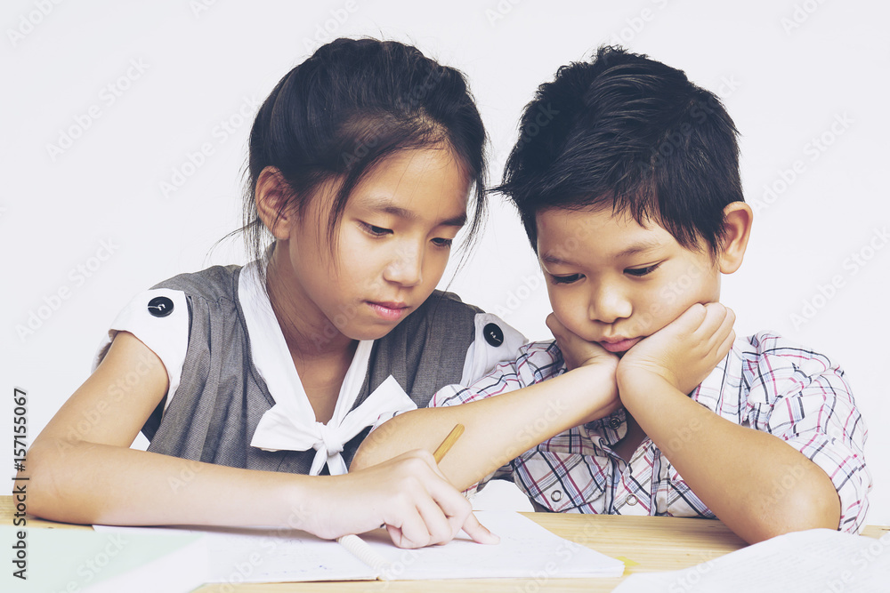 Sister try to teach her naughty younger brother to do homework isolated over white background Sister try to teach her naughty younger brother to do homework isolated over white background