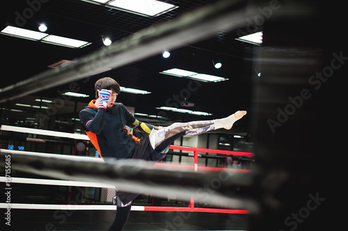 Professional Muay Thai fighter. Male boxer in training sportswear, an exercise in sports hall, fight with a shadow in ring, Strike testing © evgeniykleymenov