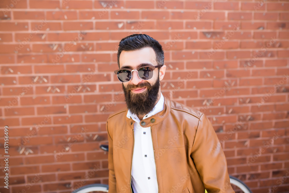 Close-up portrait of a brutal bearded man on brick wall background. Young stylish hipster posing in the street. Close-up portrait of a brutal bearded man on brick wall background. Young stylish hipster posing in the street.