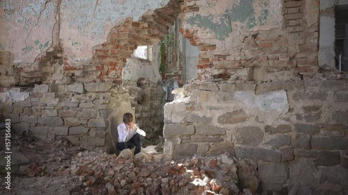 The boy hides and cries, in a ruined building after the war, lost, fear, loneliness, threat, loss