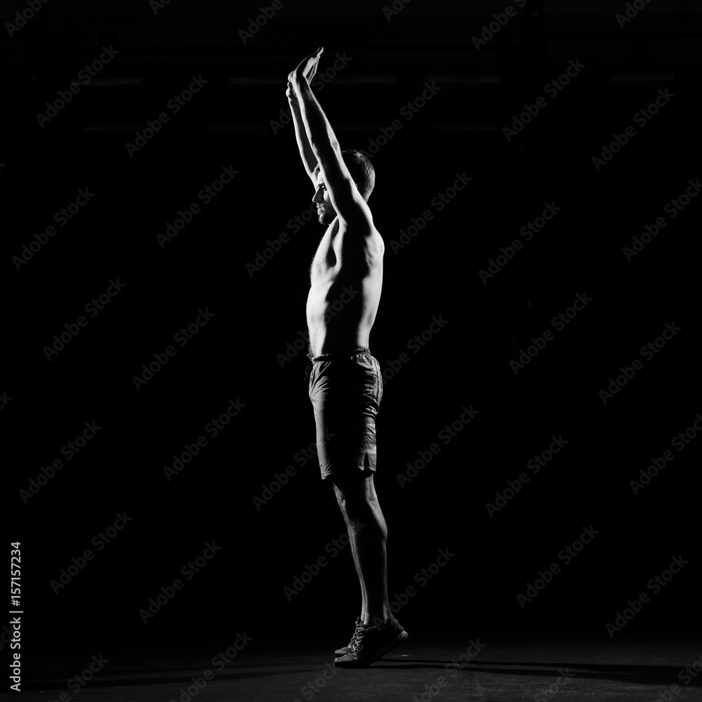 Fitness training. Male althete doing exercises in dark gym. Sporty man. Fitness training. Male althete doing exercises in dark gym. Sporty man.