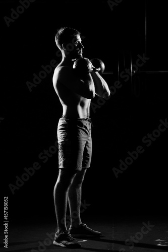 Fitness training. Man doing exercises with weights in dark gym. © Dmitry Tsvetkov