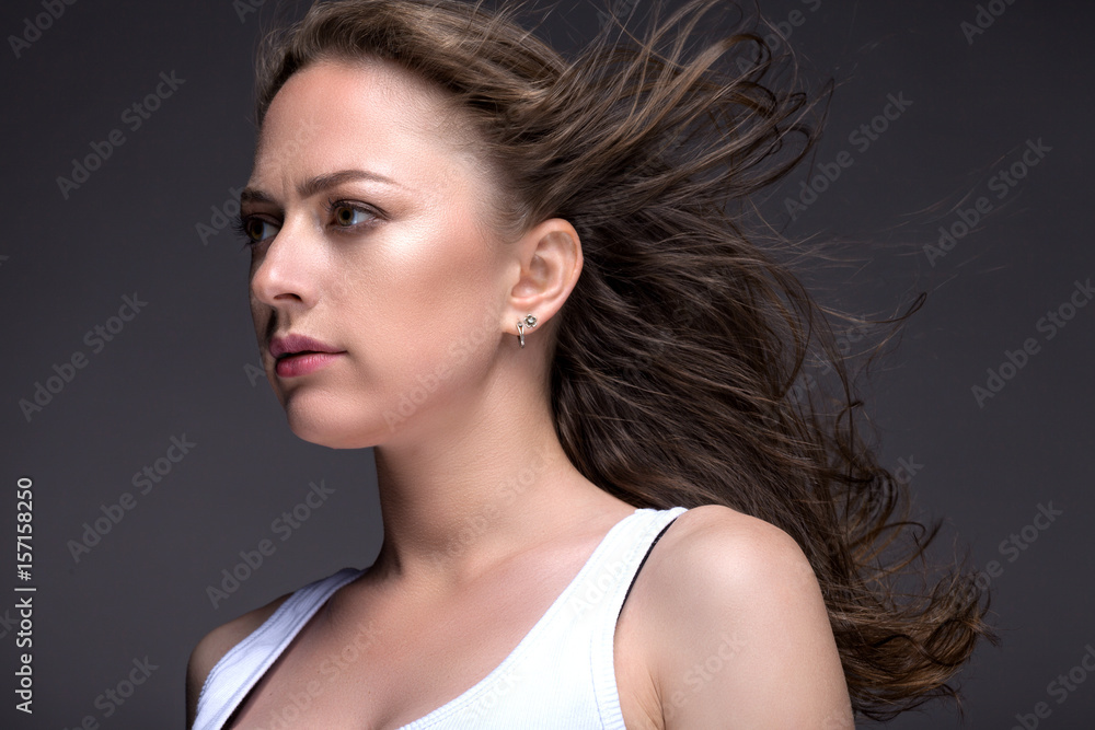 Portrait of a young woman on a gray background in a white tank top Portrait of a young woman on a gray background in a white tank top