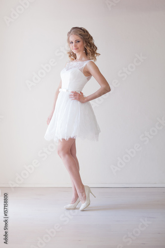 girl in a wedding dress stands in a white room wedding