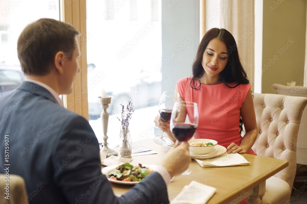 Beautiful romantic couple having dinner with wine in bright luxury restaurant Beautiful romantic couple having dinner with wine in bright luxury restaurant