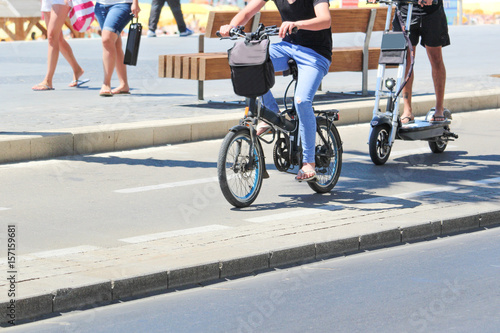 Two men riding on electric bicycles and electric scooter