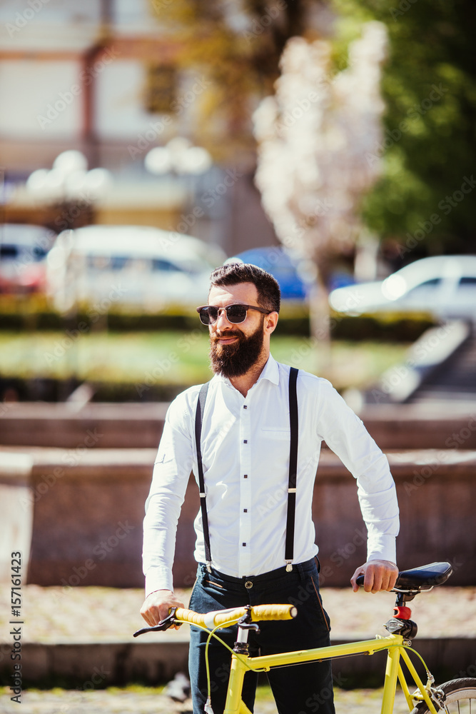 Young stylish bearded man with a fixie bicycle on the sunny street Young stylish bearded man with a fixie bicycle on the sunny street