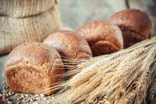 Fresh bread buns, wheat ears and sack of flour.