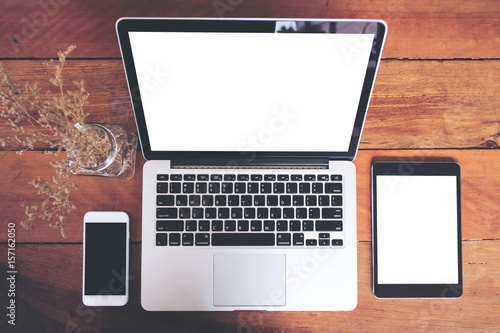 Black and white mockup image of mobile phone , laptop and tablet on vintage wood table background
