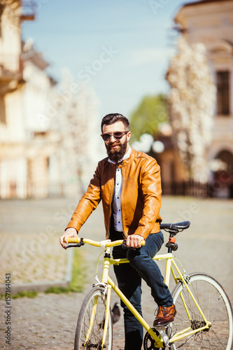 Handsome bearded young man in sunglasses on bike in the city. Bicycle concept