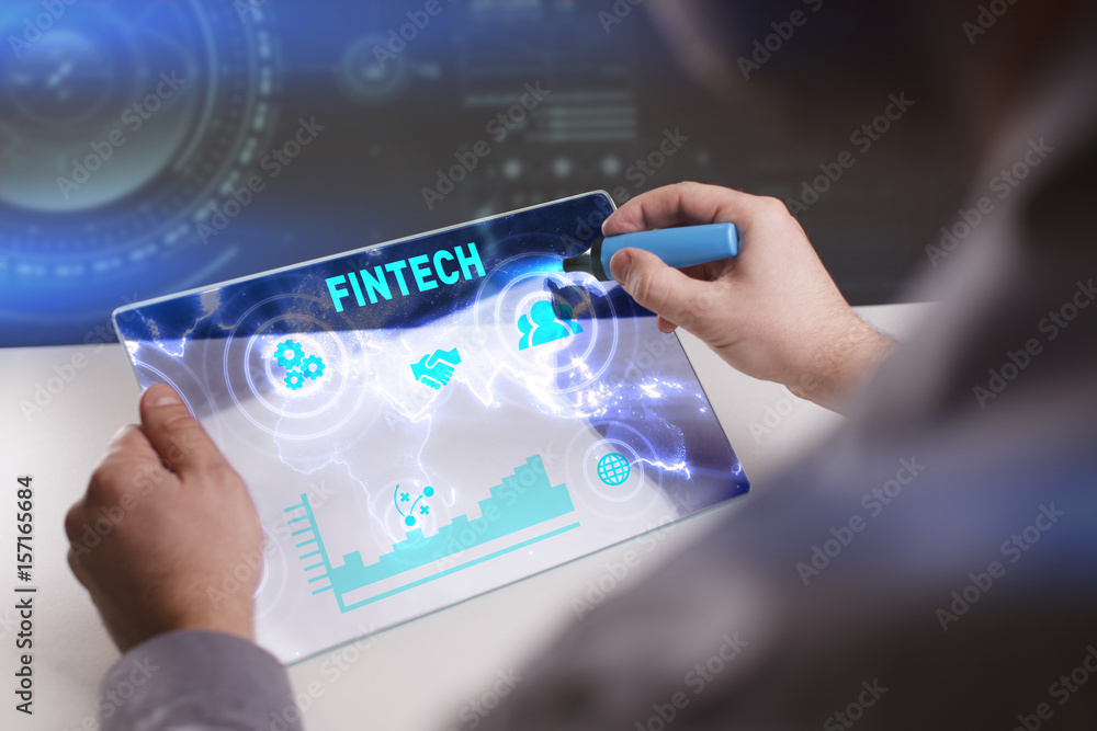 Business, Technology, Internet and network concept. Young businessman working on a virtual screen of the future and sees the inscription: Fintech Business, Technology, Internet and network concept. Young businessman working on a virtual screen of the future and sees the inscription: Fintech