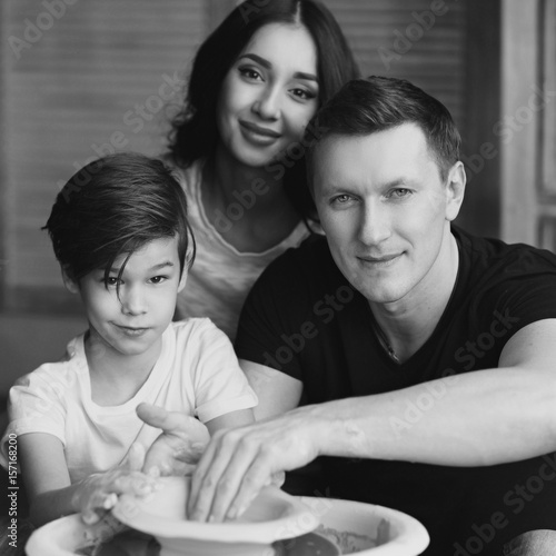 Young caucasian family working on potter's wheel. Handsome father, beautiful mother and young son. Pottery classes. Dirty Hands. Parents enjoying time together with their child.