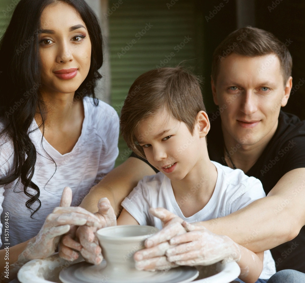 Family working on pottery wheel. Brunette caucasian mother, handsome father and son having great time together and enjoy making clay pot Family working on pottery wheel. Brunette caucasian mother, handsome father and son having great time together and enjoy making clay pot