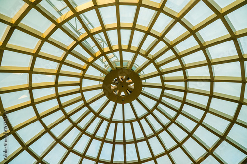 Transparent glass dome of a modern hotel. Metal frame frame, glass through which the blue sky is visible and illuminates the lobby of the hotel or business center.