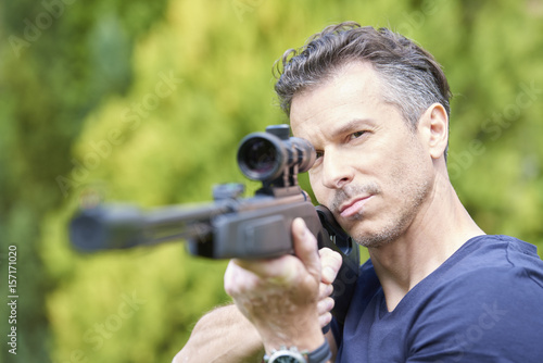 Aiming at a target. Shot of a man with airgun practicing at the shooting range.  photo