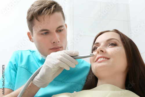 Male dentist with dental turbine and female patient in clinic