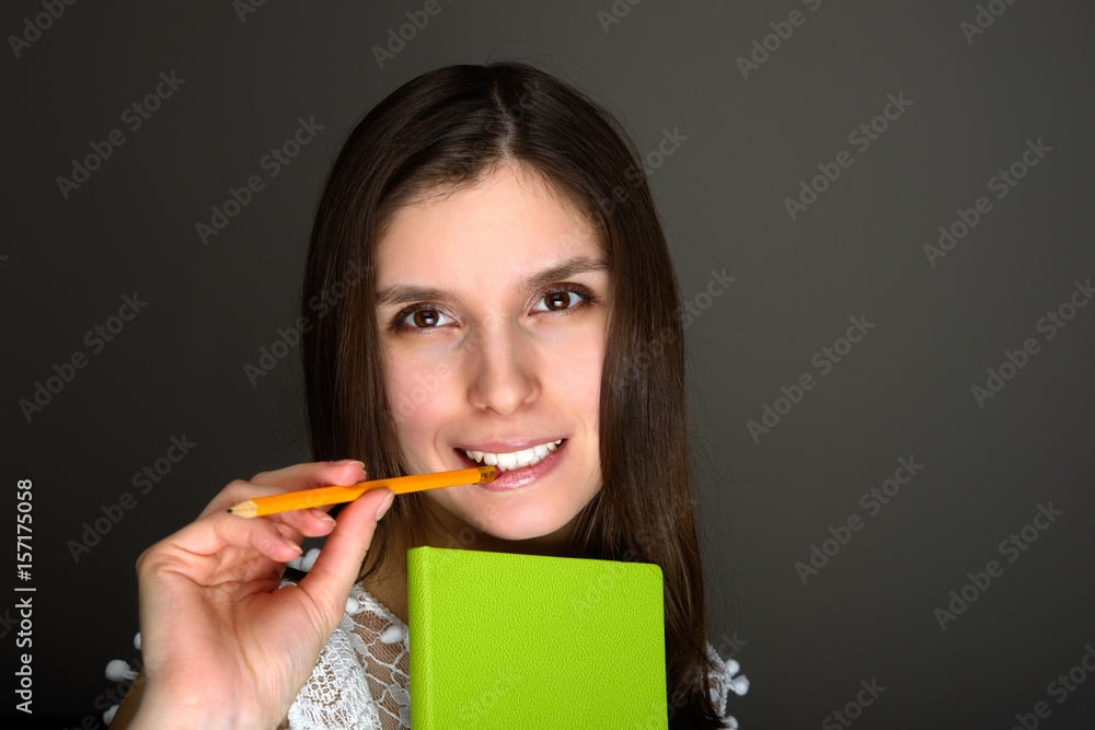 Portrait of young brunette female chewning pencil Portrait of young brunette female chewning pencil