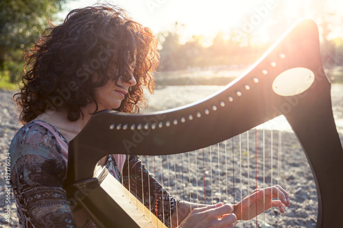 Fotografija beautiful curly hair woman playing the harp