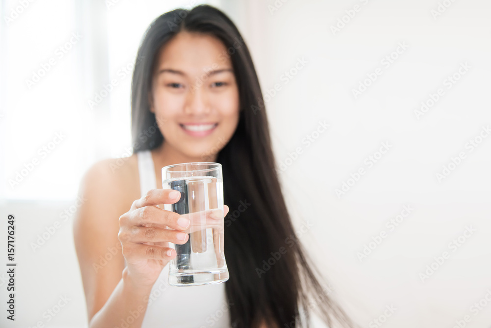 Close up Asian Woman holding glass of water. Beautiful girl smiling on bed in the morning. Close up Asian Woman holding glass of water. Beautiful girl smiling on bed in the morning.