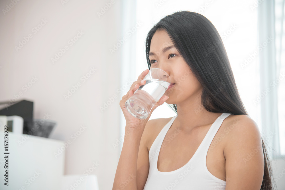 Asian woman drinking water at her bedroom. Asian woman drinking water at her bedroom.