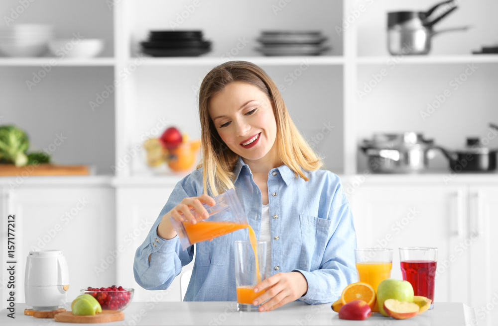 Beautiful woman preparing fresh juice in kitchen