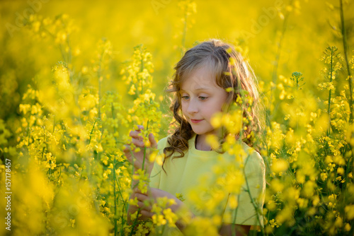 The beautiful girl in a yellow dress on the blossoming field