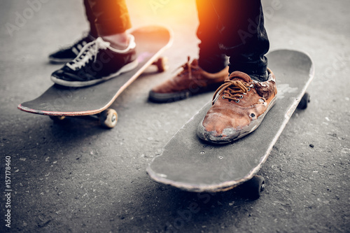 Group of friends skateboarders rest on the street and skateboard, shoes in holes and scuffs. Concept street hooligans. Monochrome and high contrast.