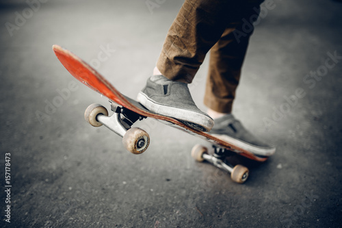 Close-up of a male guy on a skateboard doing trick kicks in shoes. The concept of doing street sports skateboarding. Sunset, toning pictures.