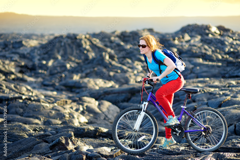 Young tourist cycling on lava field on Hawaii. Female hiker heading to lava viewing area at Kalapana town on her bike.