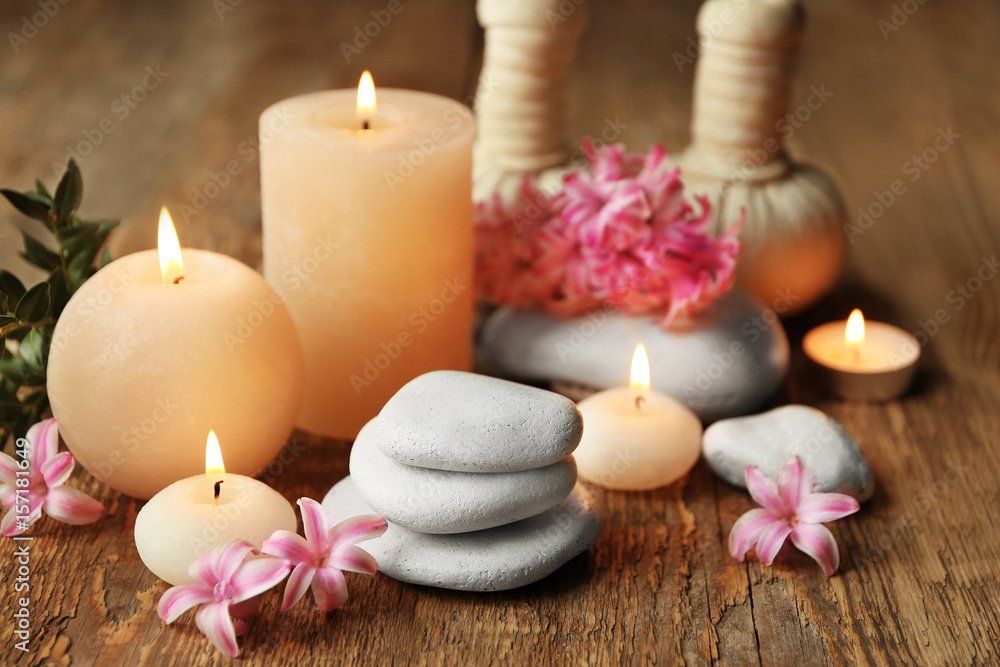 Beautiful spa composition with stones, flowers and candles on wooden background
