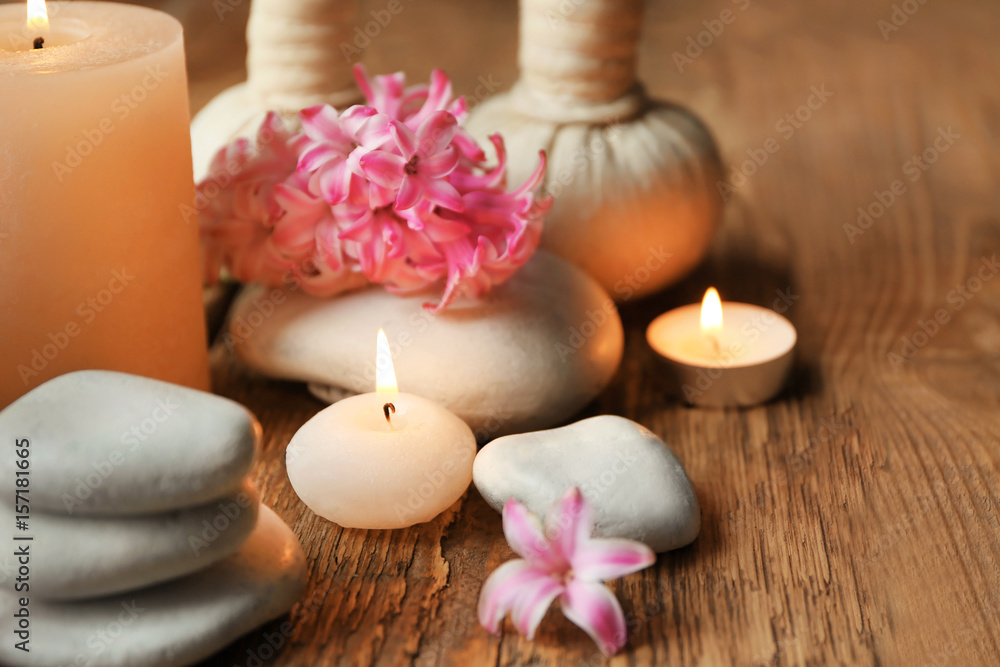 Beautiful spa composition with stones, flowers and candles on wooden background