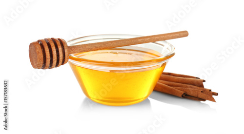 Cinnamon sticks and honey in glass bowl isolated on white