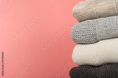 Knitted wool sweaters. Pile of knitted winter, autumn clothes on red,, wooden background, sweaters, knitwear, space for text
