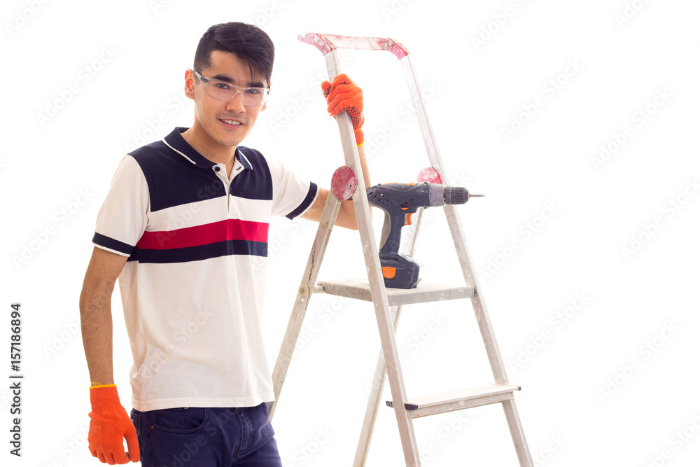 Young man with electric screwdriver and ledder Young man with electric screwdriver and ledder