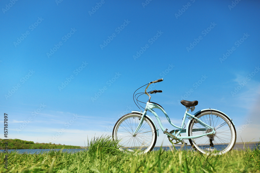 Blue bicycle standing on grass near river