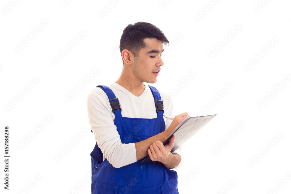 Young man in blue overall holding pen and folder Young man in blue overall holding pen and folder