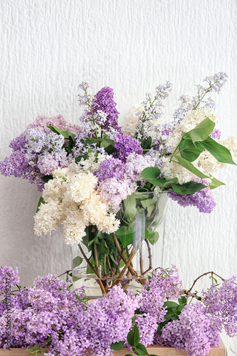 Glass vase with beautiful lilac flowers on table