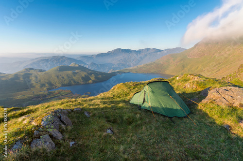 Wildcamping site with tent overlooking Stickle Tarn in the English Lake District on a sunny morning.