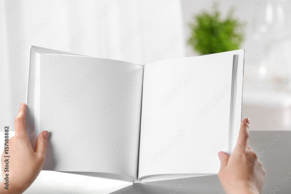 Female hands holding opened book with blank pages on light background Female hands holding opened book with blank pages on light background