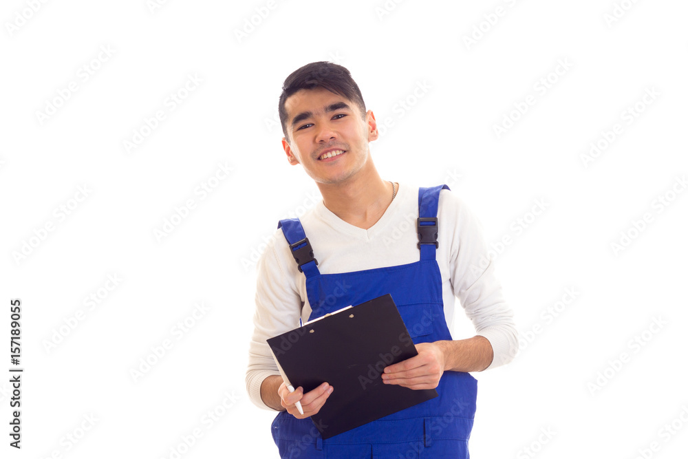 Young man in blue overall holding pen and folder Young man in blue overall holding pen and folder