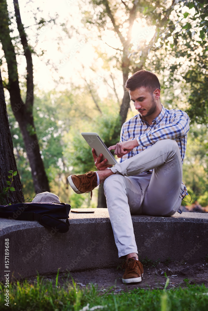 Fototapeta premium Student with tablet computer working in the park