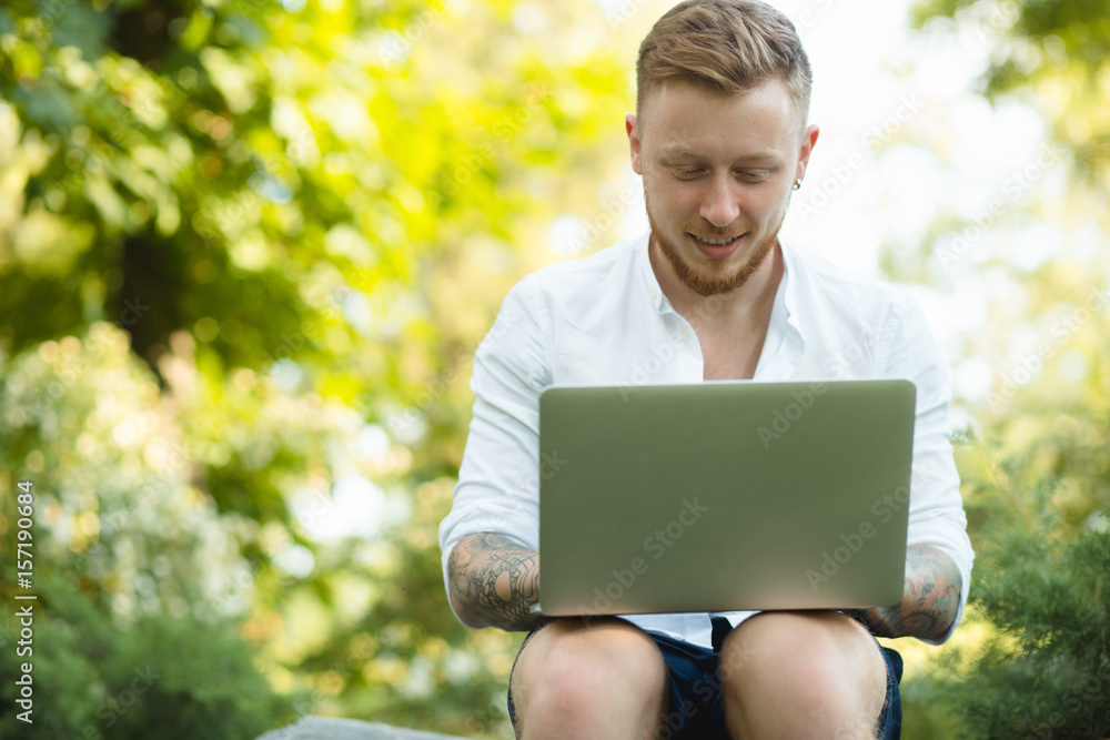 Man enjoying to freelance works anywhere. He using laptop in a park. Man enjoying to freelance works anywhere. He using laptop in a park.