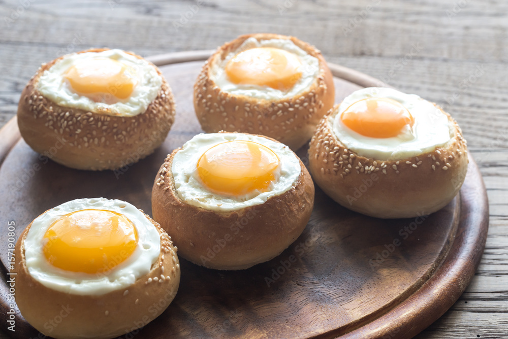 Egg-in-a-hole buns on the wooden board Egg-in-a-hole buns on the wooden board