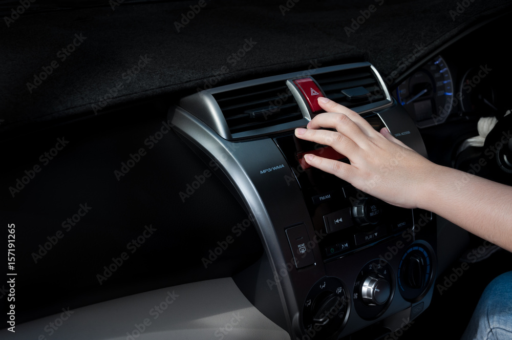 woman finger pressing car emergency light button in car